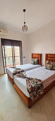 two beds in a large room with two windows at Appartement deux chambres a gueliz in Marrakech