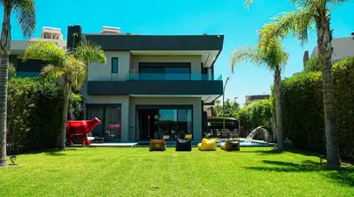 a house with palm trees in front of a yard at Villa contemporaine in Marrakech