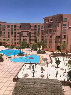 a large building with a pool with tables and umbrellas at résidence ATLASS in Marrakech