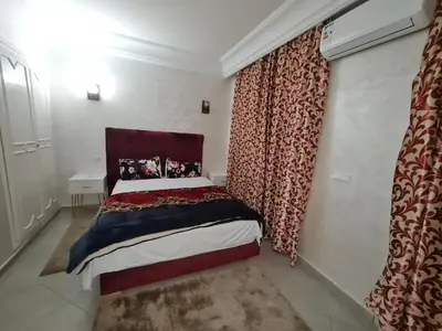 a bedroom with a bed and a window with curtains at résidence ATLASS in Marrakech