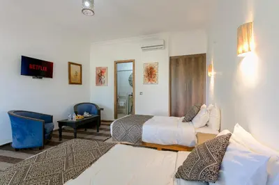 a hotel room with two beds and a chair at Abraj Bladi Resort in Marrakech