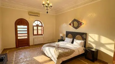 a bedroom with a bed and a window and a chandelier at Charming Luxury Villa - Pool & Hot Tub in Marrakech