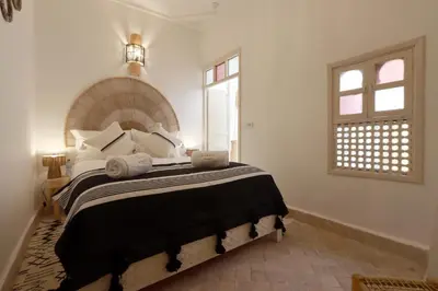 a bedroom with a large bed with black and white pillows at Riad El Charsa, logement entier 4 à 6 personnes, proche Jemaa El Fna, Rooftop et bassin chauffé in Marrakech