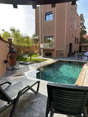 a swimming pool with a chair and a house at Villa Caprice Palace in city center in Marrakech