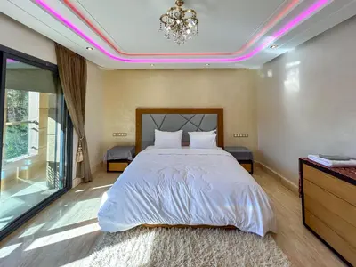 a bedroom with a large bed and a chandelier at Villa Caprice Palace in city center in Marrakech