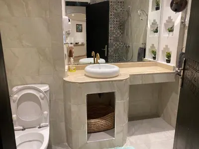 a bathroom with a toilet and a sink and a mirror at Appartement moderne à 5piscines in Marrakech