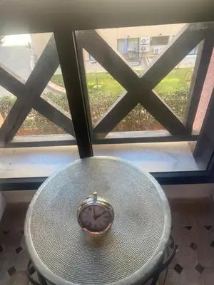 a clock sitting on a table in front of a window at Appartement moderne à 5piscines in Marrakech