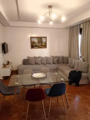 a living room with a couch and a table and chairs at Appartement moderne à 5piscines in Marrakech