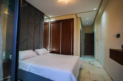a bedroom with a white bed with a wooden headboard at New and luxurious apartment with a pool in Marrakech