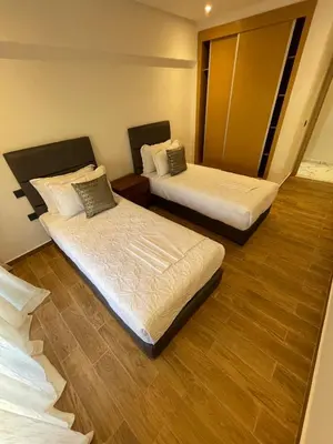 two beds in a room with wooden floors at Luxury 2BR Pool Apartement Marrakech in Marrakech