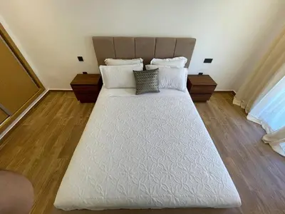 a large white bed in a room with wooden floors at Luxury 2BR Pool Apartement Marrakech in Marrakech