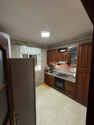 a kitchen with wooden cabinets and a refrigerator at Appartement près de la gare de Marrakech in Marrakech