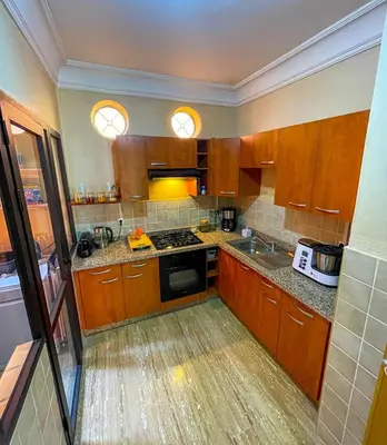 a kitchen with wooden cabinets and a stove top oven at Stunning Patios & Gardens Apartment in Marrakech