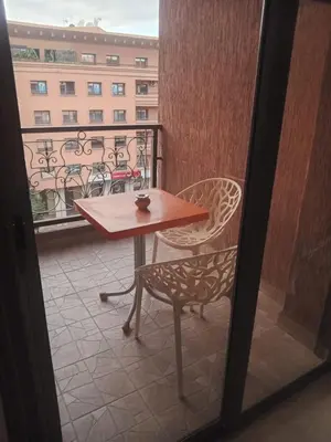 a table and chair on a balcony with a view of a building at Résidence SOFIA PALMERAIE in Marrakech