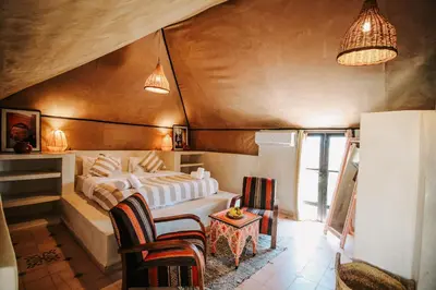 a bedroom with a bed and chairs in a room at Hotel & Spa La Ferme El Dar in Marrakech