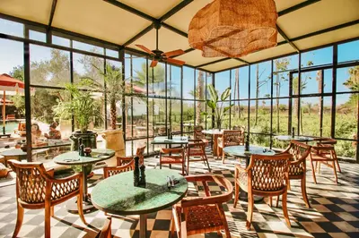 a restaurant with tables and chairs and windows at Hotel & Spa La Ferme El Dar in Marrakech