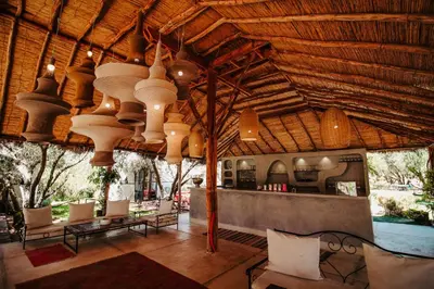 a restaurant with a large wooden ceiling with chairs and tables at Hotel & Spa La Ferme El Dar in Marrakech