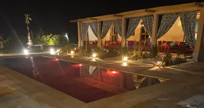 a pool with lights in front of a building at night at Maison de vacances avec piscine in Marrakech