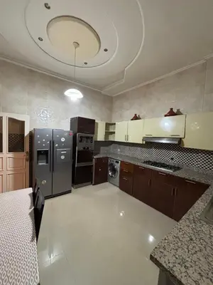 a large kitchen with brown cabinets and a silver refrigerator at Villa Saber in Marrakech