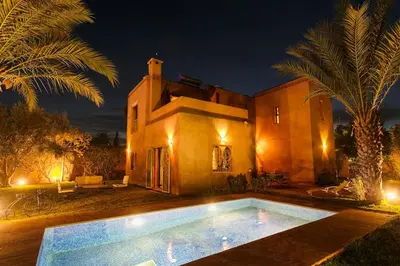 a house with a swimming pool in front of it at night at Your Traditional Marrakchi Villa in Marrakech