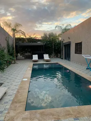 a swimming pool with two chairs and a house at Villa Marrakech in Marrakech