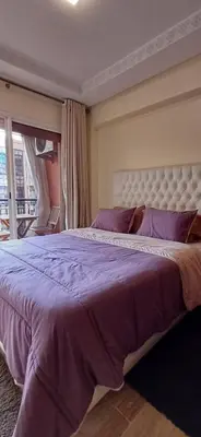 a bedroom with a large bed with purple sheets at Résidence Hamza - Appartement familial in Marrakech