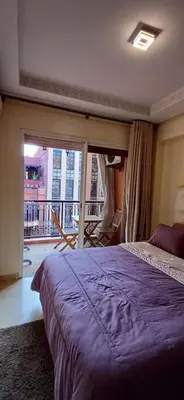 a bedroom with a large purple bed and a balcony at Résidence Hamza - Appartement familial in Marrakech