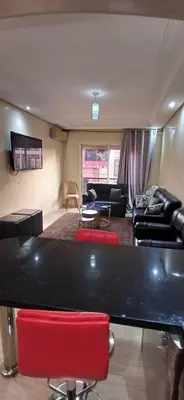 a living room with a table and red chairs at Résidence Hamza - Appartement familial in Marrakech