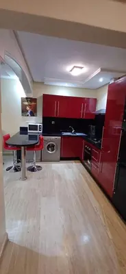 a kitchen with red cabinets and a table in a room at Résidence Hamza - Appartement familial in Marrakech