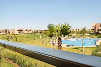 a view of a resort with a pool and palm trees at Appartement prestigia golf accès piscine in Marrakech