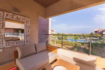 a living room with a couch and a large window at Appartement prestigia golf accès piscine in Marrakech