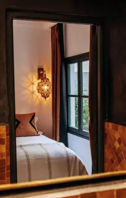 a mirror reflecting a bedroom with a bed and a window at Riad Beltza - 