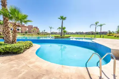 a swimming pool with palm trees in a resort at Apparemment haute standing golf prestigia in Marrakech