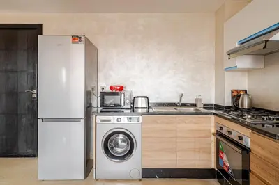 a kitchen with a white refrigerator and a washing machine at Cosy appartement au centre ville hivernage marrakech in Marrakech