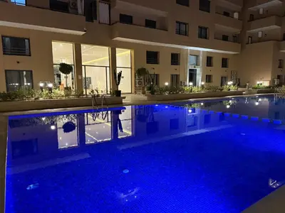 a swimming pool in front of a building at night at Golden Palm Resort in Marrakech
