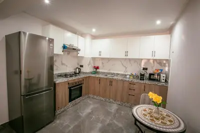 a kitchen with white cabinets and a table and a refrigerator at Golden Palm Resort in Marrakech
