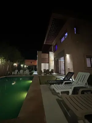 a pool with lounge chairs next to a building at night at villa Marrakesh in Marrakech
