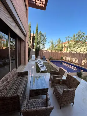 a patio with wicker chairs and a table and a pool at villa Marrakesh in Marrakech