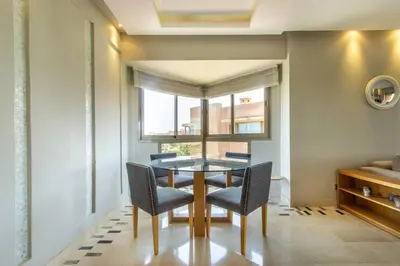 a dining room with a table and chairs and a window at Stylish In Prestigia Area Pool View in Marrakech