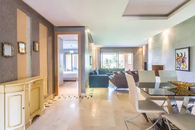 a living room with a dining table and a couch at Front de piscine en rez de Jardin a Prestigia in Marrakech