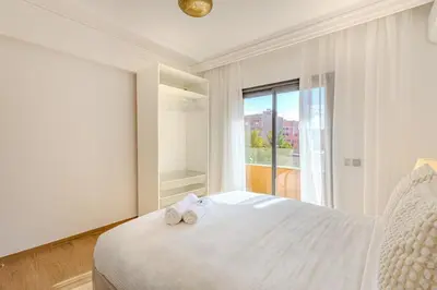 a white bedroom with a bed with towels on it at New! appt Nour Confort avec piscine & wifi in Marrakech