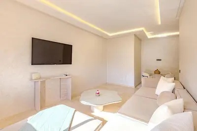 a living room with a couch and a tv on the wall at New! appt Nour Confort avec piscine & wifi in Marrakech