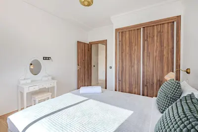 a white bedroom with a bed and a wooden door at New! appt Nour Confort avec piscine & wifi in Marrakech
