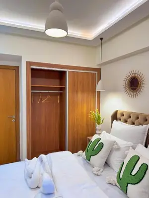 a bedroom with a bed with white sheets and cactus pillows at Appartement luxe au cœur de Marrakech in Marrakech