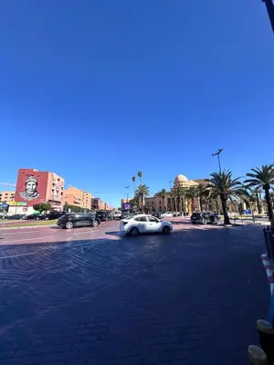 a white car driving down a street with palm trees at Appartement luxe au cœur de Marrakech in Marrakech