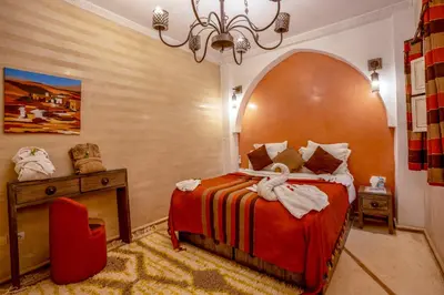 a bedroom with a bed and a table and a chandelier at Dar Flora in Marrakech