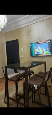 a dining room table with two chairs and a tv on the wall at Cozy appartment in Marrakech