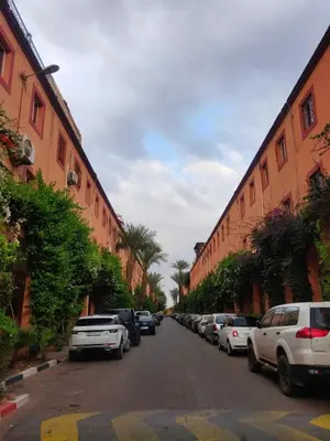 a street with cars parked next to tall buildings at APPARTEMENT DAR MARRAKECh G27 N7 in Marrakech