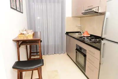 a small kitchen with a table and a refrigerator at Welcome Home! in Marrakech