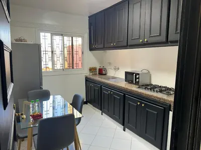 a kitchen with black cabinets and a table with chairs at Calm Oasis with Private Terrace in Marrakech
